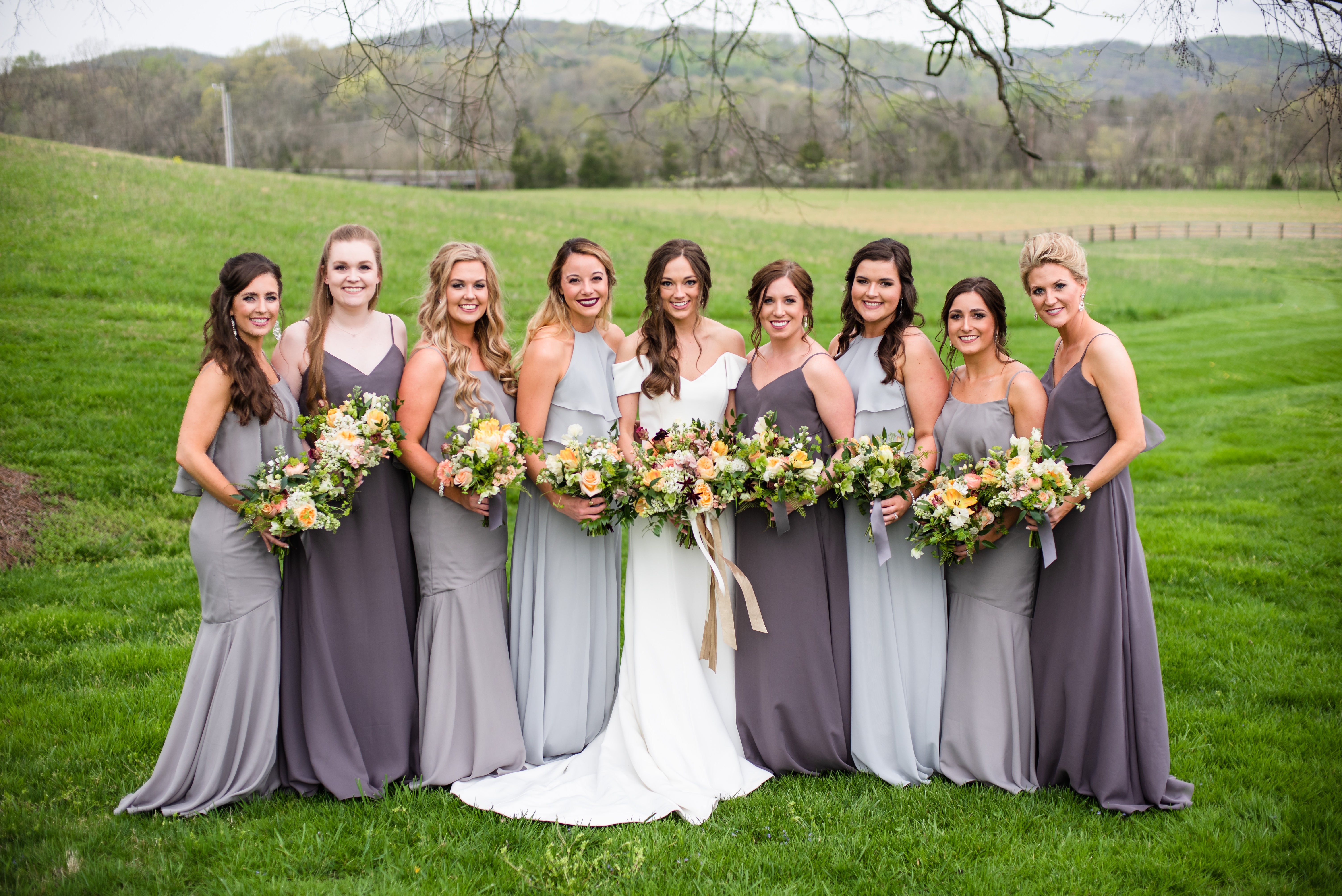 Allie Coode's bridal party wearing mix-and-match grey bridesmaid dresses outdoors